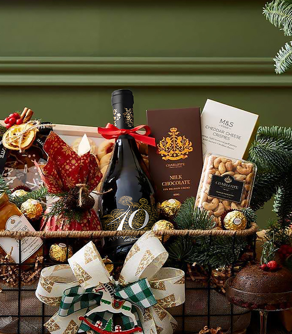 Charlotte gift hamper with red wine, milk chocolate, roasted cashews, holiday cake, and Christmas ribbon