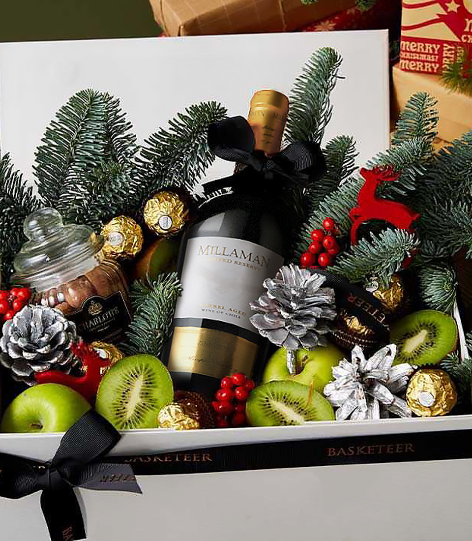 Elegant holiday gift box with Millaman wine, Ferrero Rocher, green apples, kiwi, pinecones, and festive winter decor