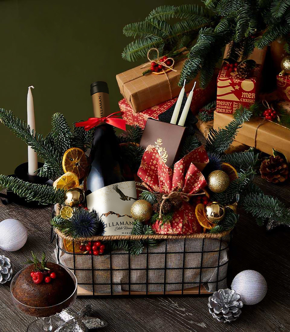 Christmas gift basket with Altamana Merlot red wine, dark chocolate bar, pine cones, dried oranges, gold baubles and festive ribbons