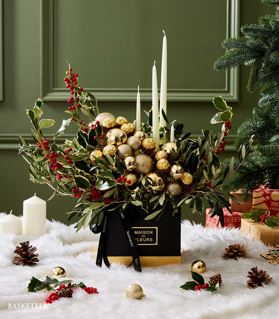 Luxurious Christmas centerpiece with golden ornaments, white candles, holly, and festive greenery, perfect for holiday celebrations.