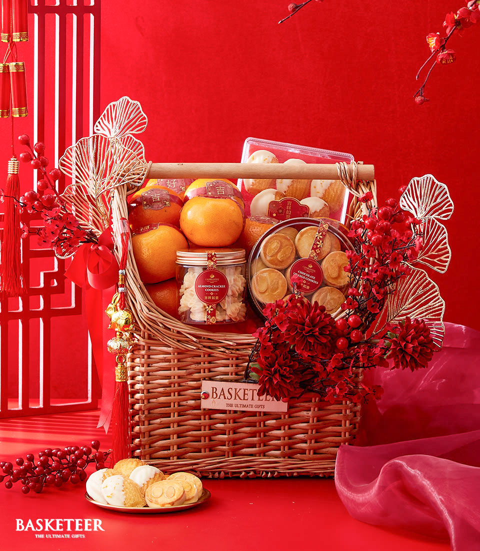 Chinese New Year Gift In Mandarin Orange, Cookies and Madeleine With Red and Gold Flowers Decoration In The Basket.