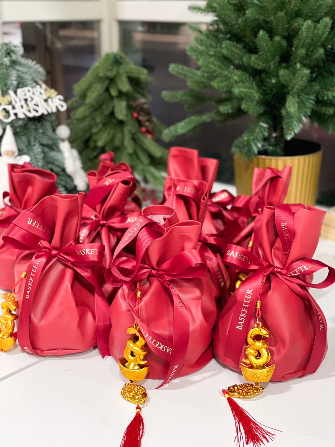 Chinese New Year Prosperity Pouches wrapped in red fabric, decorated with golden snake charms, and tied with luxurious ribbons.