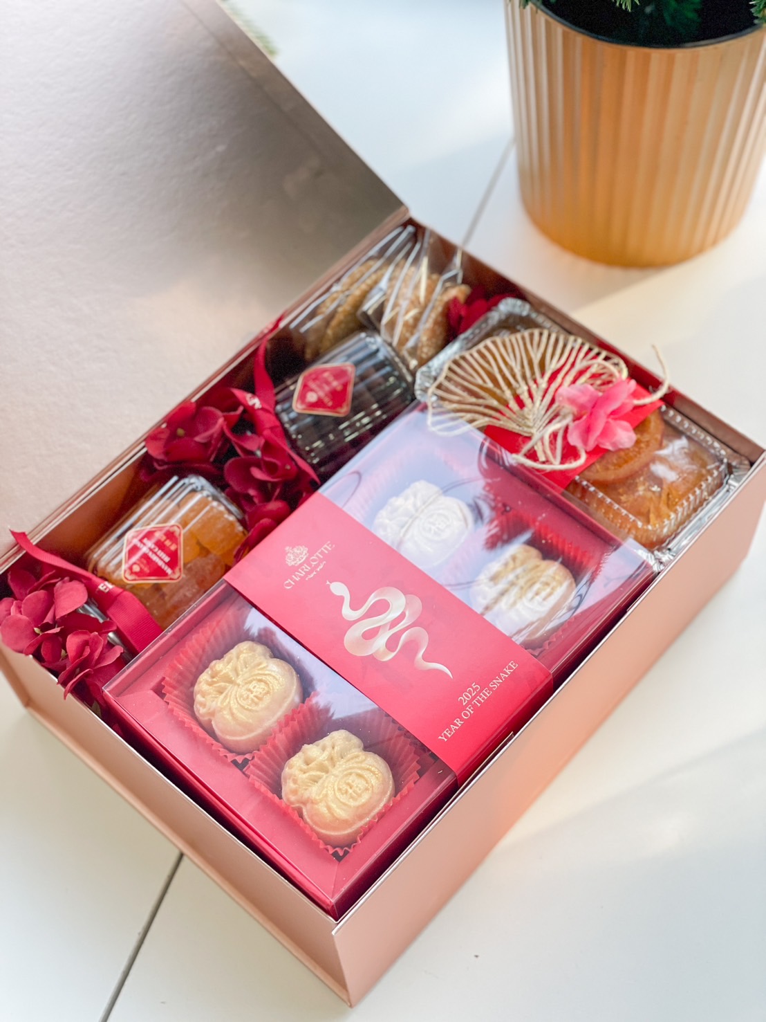 Year of the Snake gift box filled with festive treats, mini mooncakes, golden decorations, and a red-themed design for Chinese New Year.
