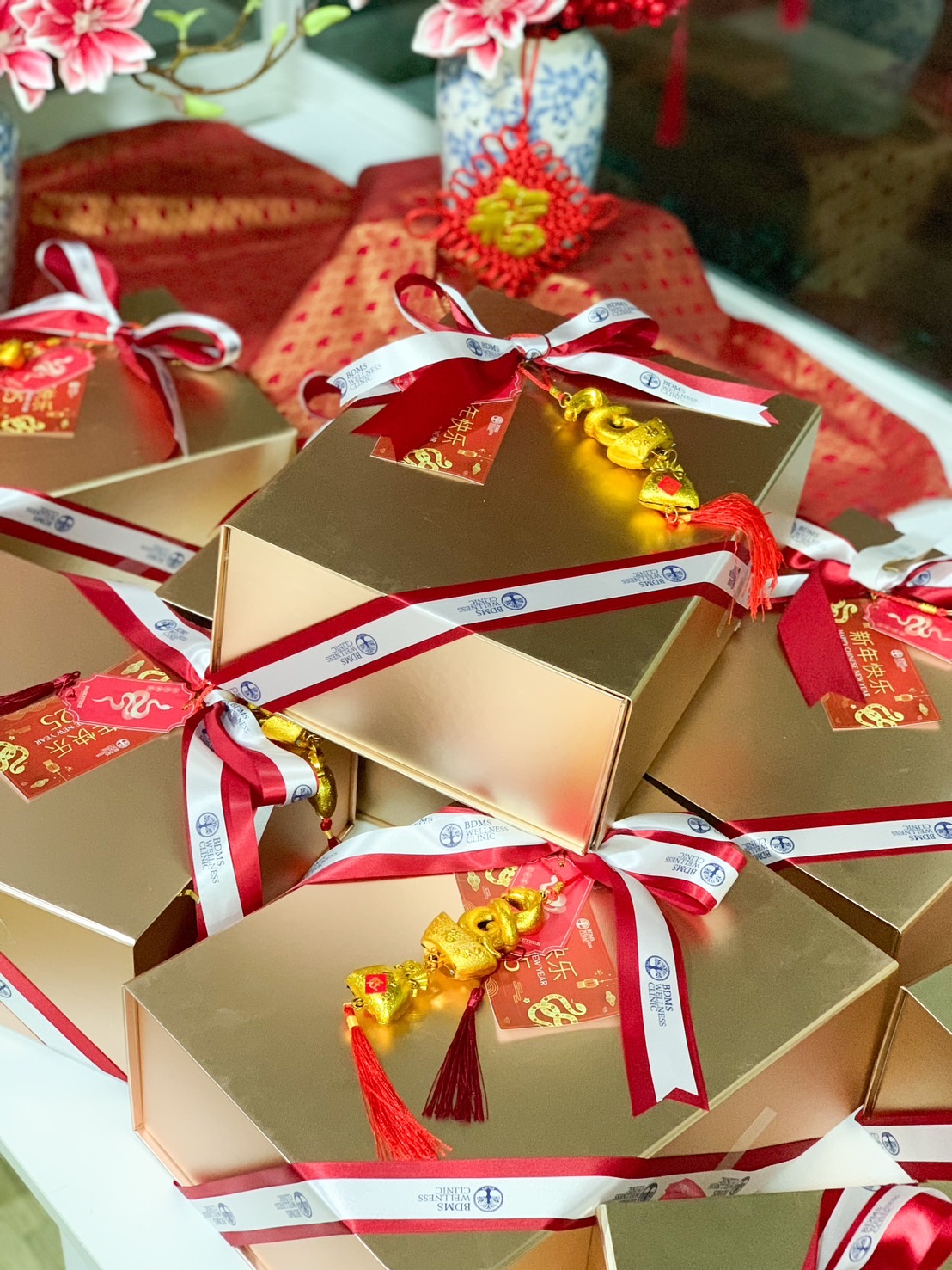 Chinese New Year gold gift box with festive red and white ribbon, good luck charm, and traditional decorations for prosperity.