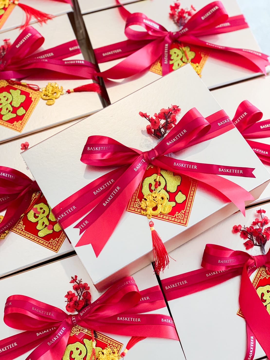 A group of elegantly wrapped gift boxes decorated with vibrant red bows, ribbons printed with the word 