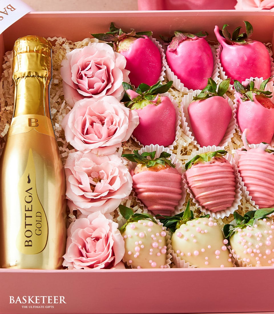 An opulent Basketeer gift box meticulously crafted to exude luxury, featuring a bottle of the exquisite Bottega Gold Prosecco. Nestled within, you'll find lush pink roses and an indulgent selection of strawberries decadently coated in pink chocolate or white chocolate adorned with pink drizzle and white pearls. These sumptuous treats rest elegantly on a bed of finely shredded paper, all beautifully presented in a box adorned with the distinguished Basketeer logo and ribbon. The Pink Chocolate Strawberries & Wine Fusion by Basketeer elevates gifting to an art form.