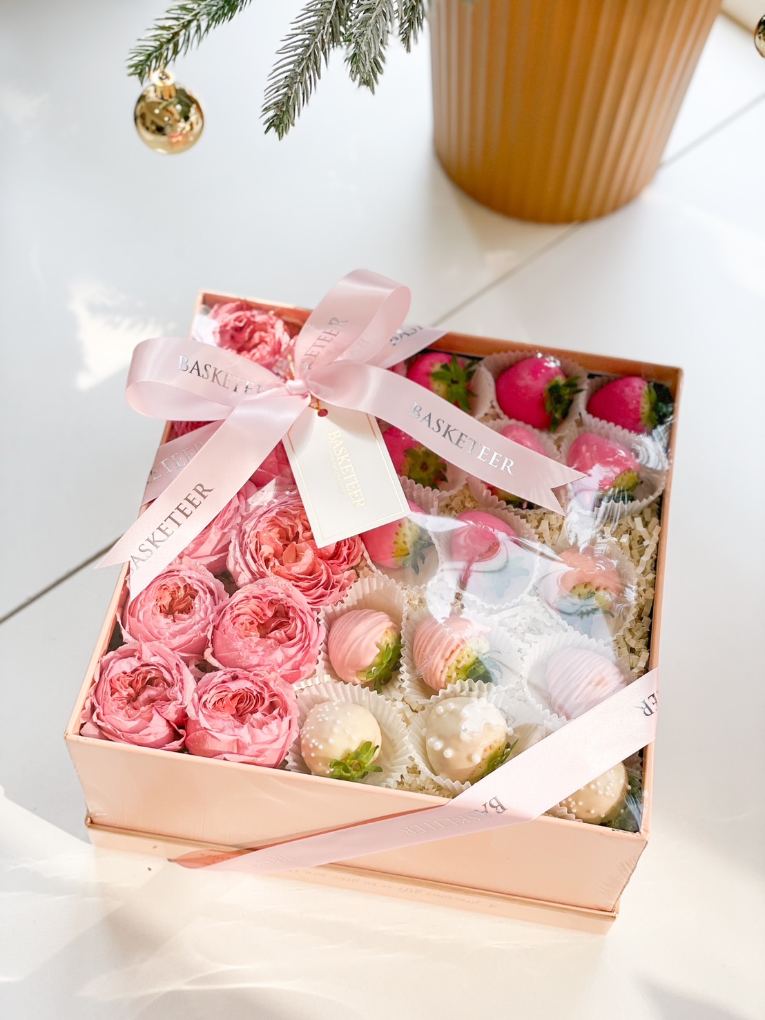 Blush-toned gift box with chocolate-dipped strawberries and preserved pink roses, tied with a soft pink ribbon.