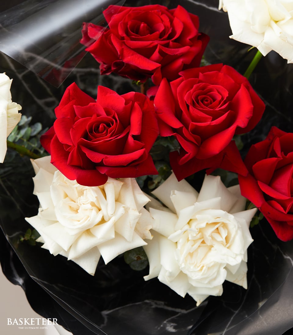 A luxurious bouquet featuring a stunning arrangement of vibrant red and pristine white roses. The lush, red blooms contrast beautifully with the immaculate white petals, creating a breathtaking visual symphony. Elegantly wrapped in sophisticated dark paper, the presentation exudes timeless elegance. The revered 