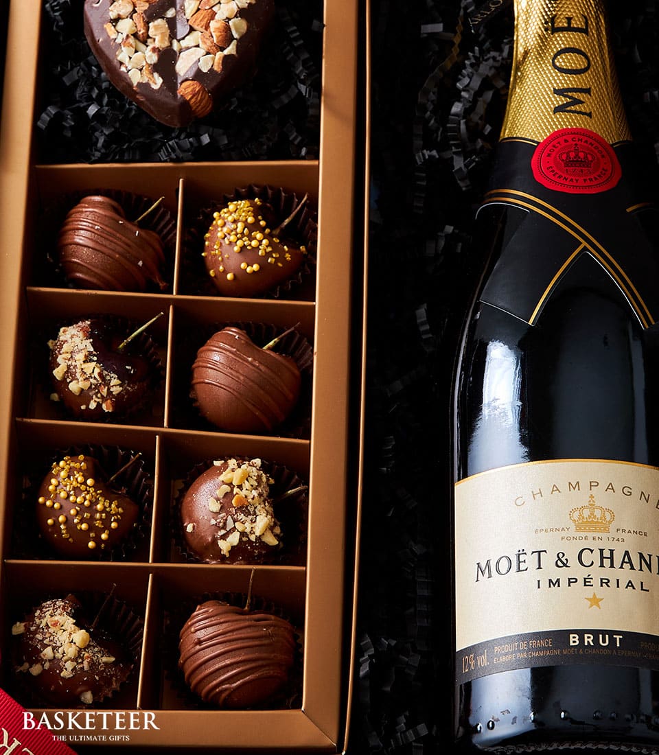 A bottle of exquisite Moët & Chandon champagne graces the scene, accompanied by a rectangular box of Basketeer gourmet chocolates. The elegant assortment features eight compartments, each cradling a meticulously crafted chocolate adorned with an array of luxurious decorations like premium nuts and delicate sprinkles. The sophisticated Basketeer ribbon adds a touch of refinement to this decadent display.