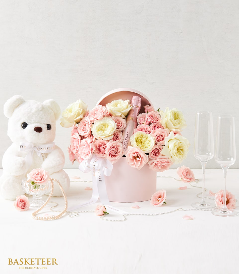 Elegant pink and white rose gift box with rosé sparkling wine and teddy bear