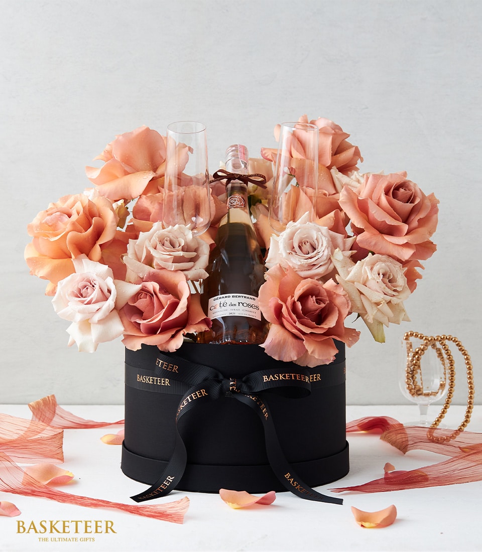 Luxury gift box with Gérard Bertrand Rosé wine and peach pink roses arranged elegantly