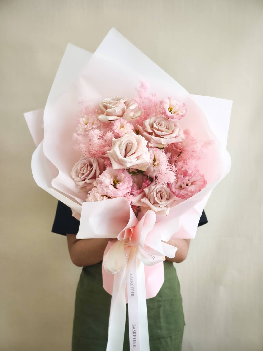 Elegant bouquet of soft pink roses, lisianthus, and pink astilbe, wrapped in pastel pink and white paper.