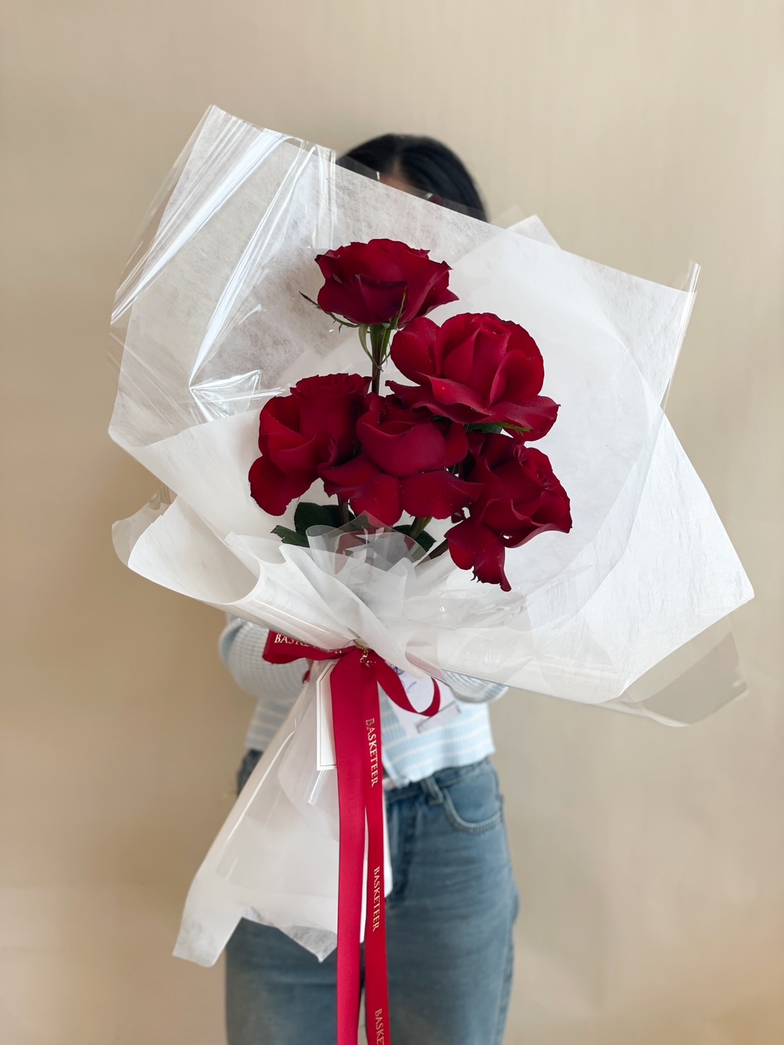 A stunning 6-red-roses bouquet, elegantly wrapped in white and clear paper, tied with a red Basketeer ribbon—a perfect romantic gift.