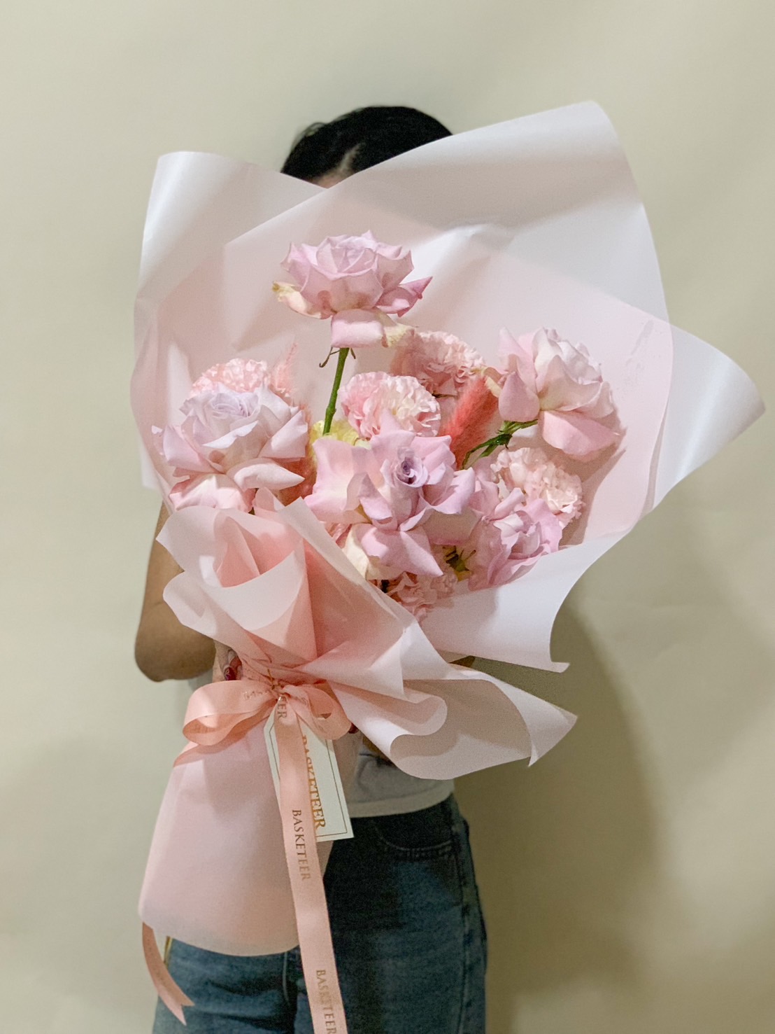 A soft pink bouquet featuring delicate roses and carnations, elegantly wrapped in pastel pink paper with a satin ribbon, exuding romance and charm.