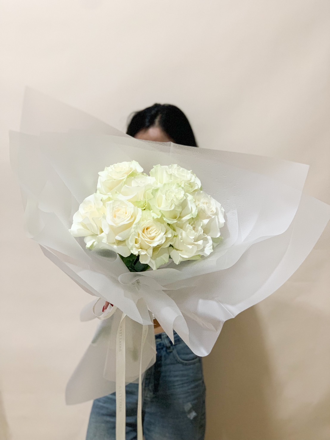 Luxurious white rose bouquet, elegantly wrapped in soft white paper, creating a timeless and sophisticated floral arrangement.