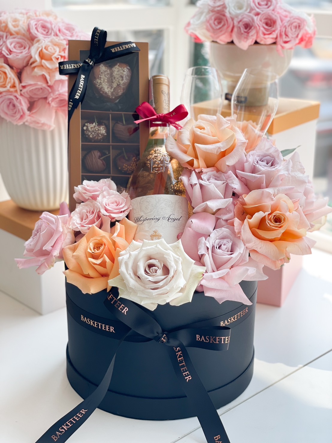 A luxury black gift box featuring Whispering Angel Rosé, preserved roses, and a gourmet chocolate selection, beautifully presented for romantic gifting.