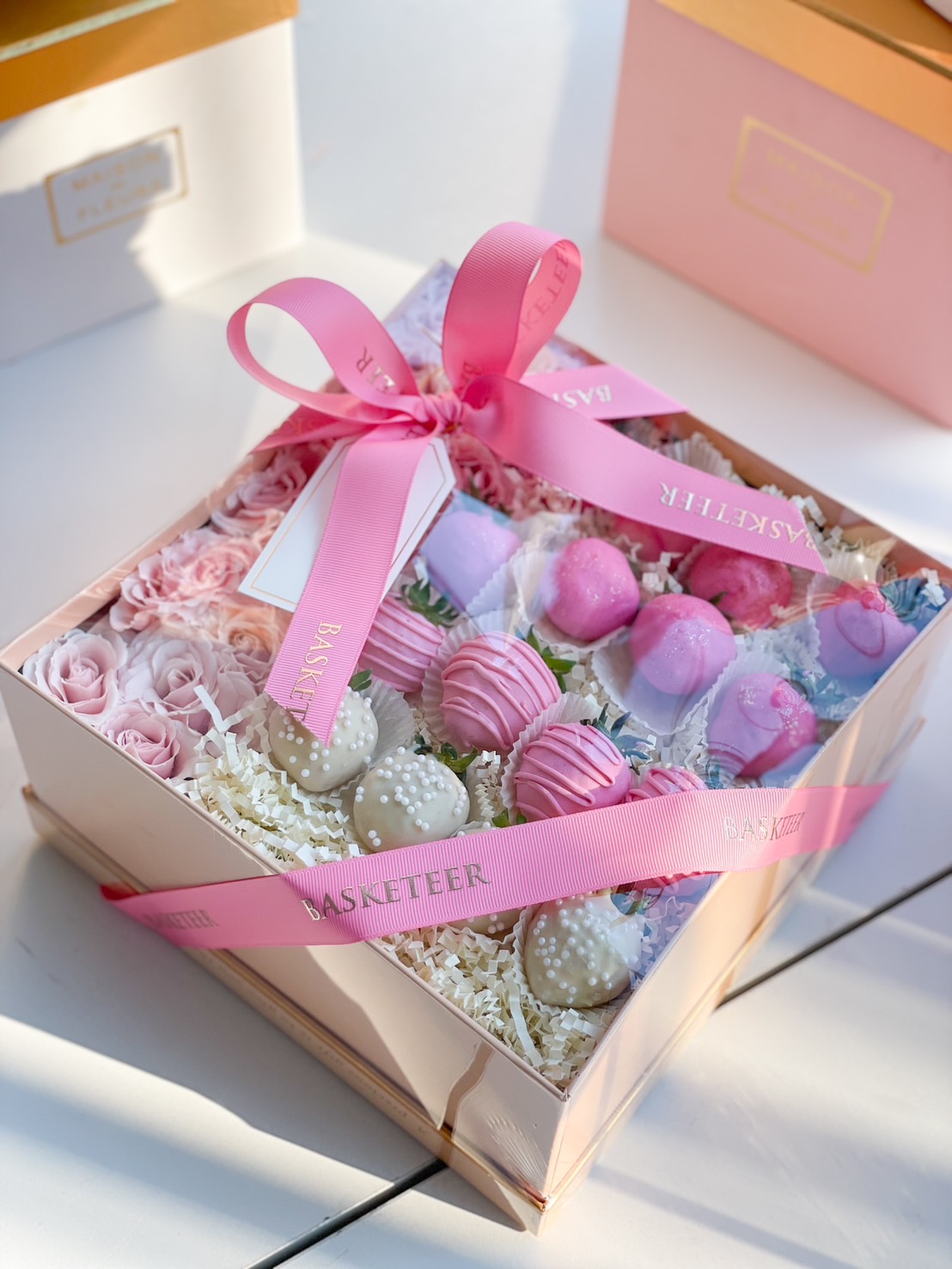 A stunning gift box of chocolate-covered strawberries in pink and white, decorated with edible pearls, fresh roses, and elegant packaging for a romantic and stylish gift.