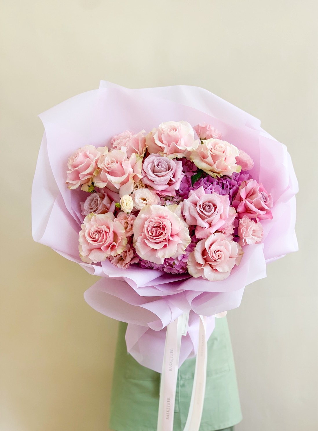 Pastel pink and purple bouquet featuring roses, spray roses, carnations, and hydrangeas in soft blush and lavender hues