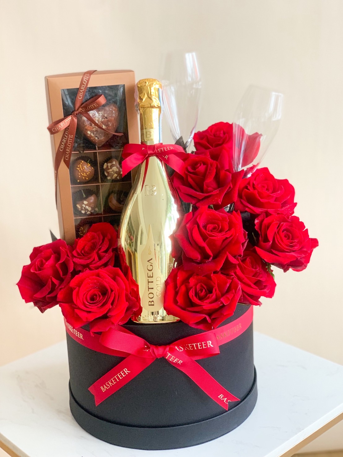 Elegant gift box with Bottega Gold Prosecco, red roses, gourmet chocolates, and champagne flutes.