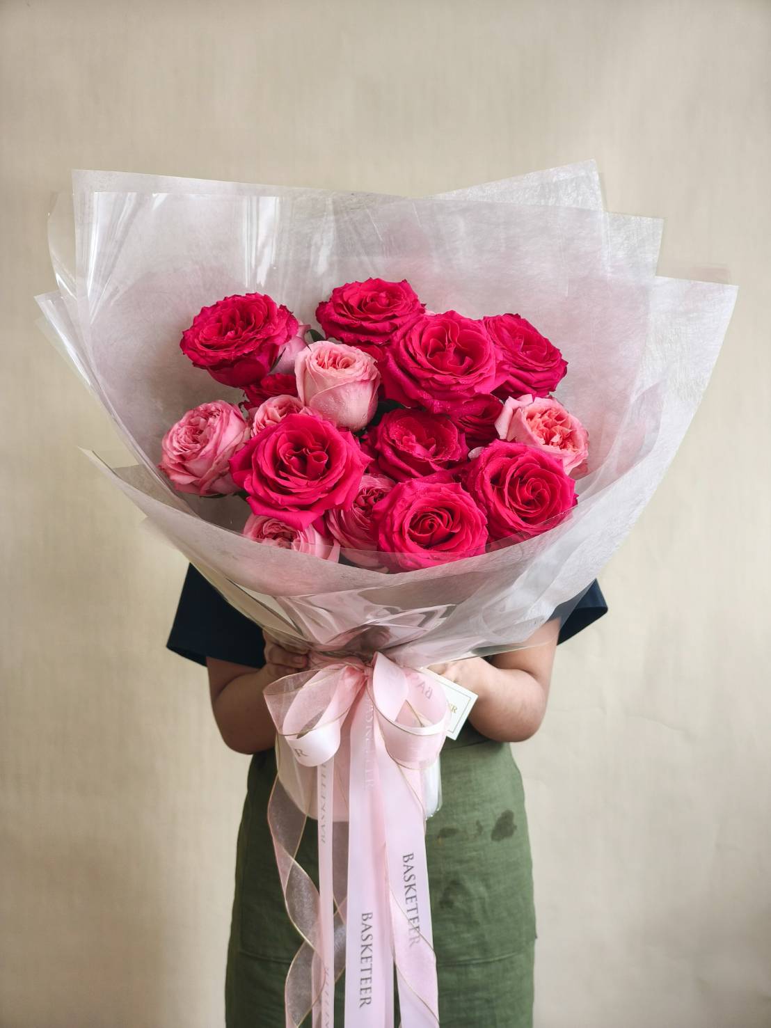 Elegant bouquet with red and pink roses wrapped in translucent white paper, finished with a pink satin ribbon.