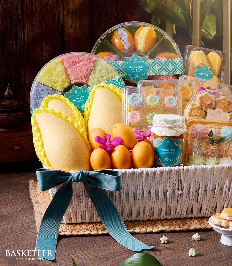 Indulge in the opulence of a Basketeer Thai Tropical Desserts Basket, exquisitely curated to delight the senses. This luxurious basket brims with vibrant and colorful Thai desserts, harmoniously paired with an array of sumptuous tropical fruits. Revel in the sweet juiciness of two large mangos and delicate small round yellow fruits, elegantly complemented by an assortment of radiant desserts encased in crystal-clear packaging. A lavish green bow graces the front of this sophisticated offering, while hints of the Basketeer logo subtly promise an experience of unparalleled indulgence and refinement.