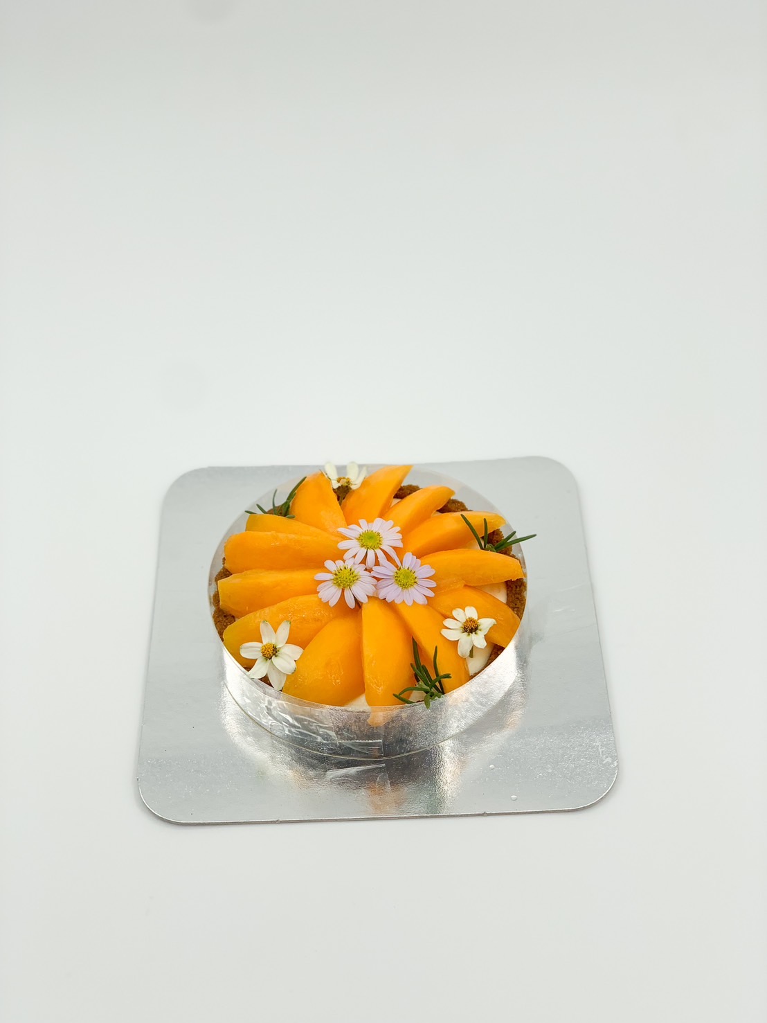 Mini marian plum tart topped with edible flowers on a silver tray.