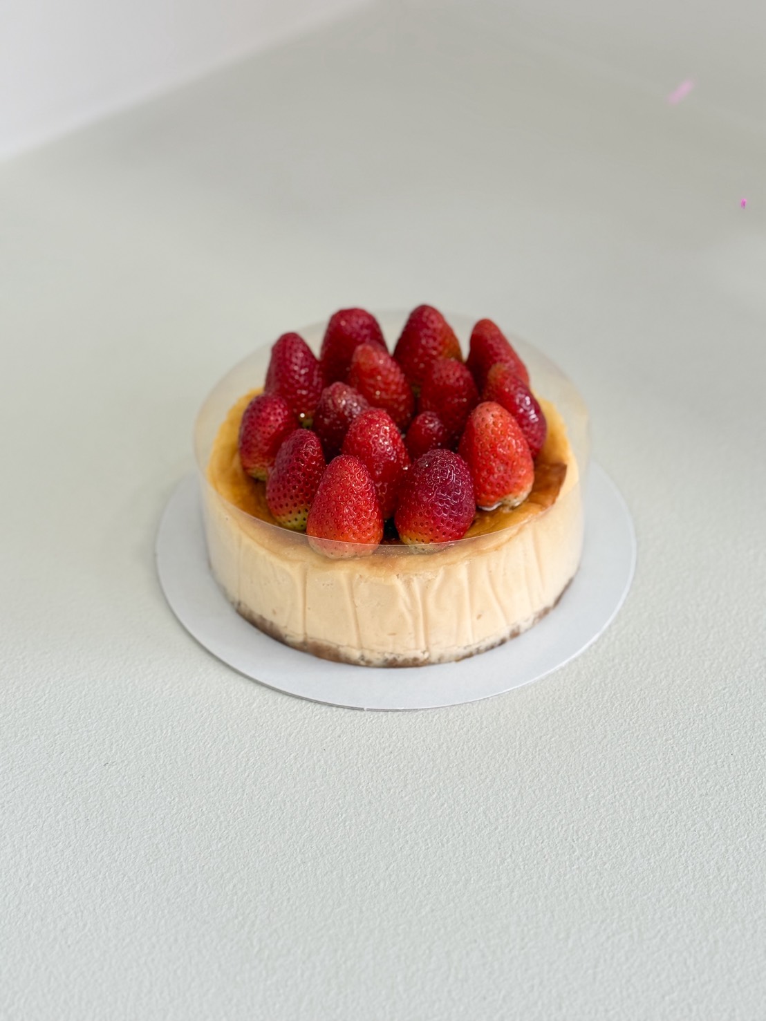 Fresh strawberry cheesecake topped with whole strawberries on a biscuit crust, perfect for birthdays and celebrations