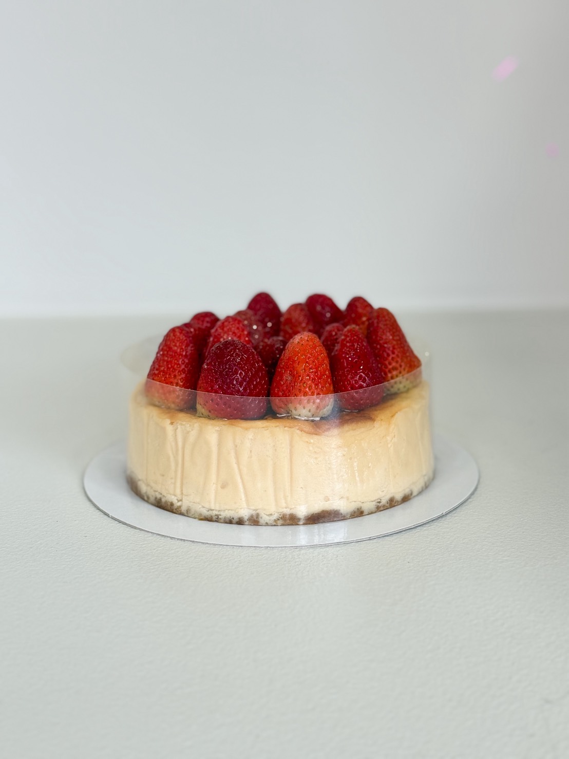 Classic strawberry cheesecake topped with whole fresh strawberries on a biscuit crust, perfect for birthdays and special occasions