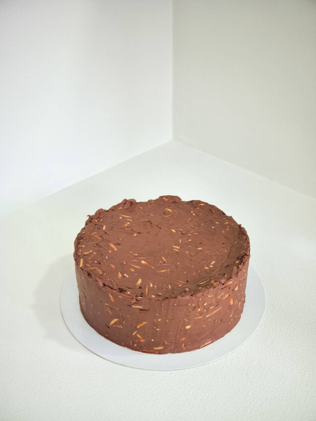 Round chocolate cake with almond crunch coating and textured chocolate frosting