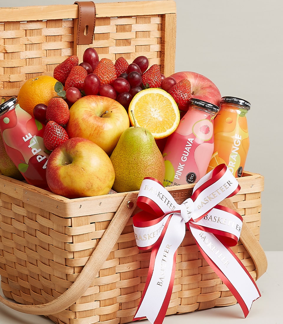 A luxurious wicker basket brimming with an exquisite selection of fresh fruits, featuring crisp apples, succulent oranges, juicy pears, plump grapes, and luscious strawberries. Complementing this opulent assortment are three elegant bottles of premium fruit juices in tantalizing flavors: Apple, Pink Guava, and Orange. The entire presentation is impeccably adorned with the signature white and red ribbon from Basketeer, adding a touch of sophistication to this indulgent offering.
