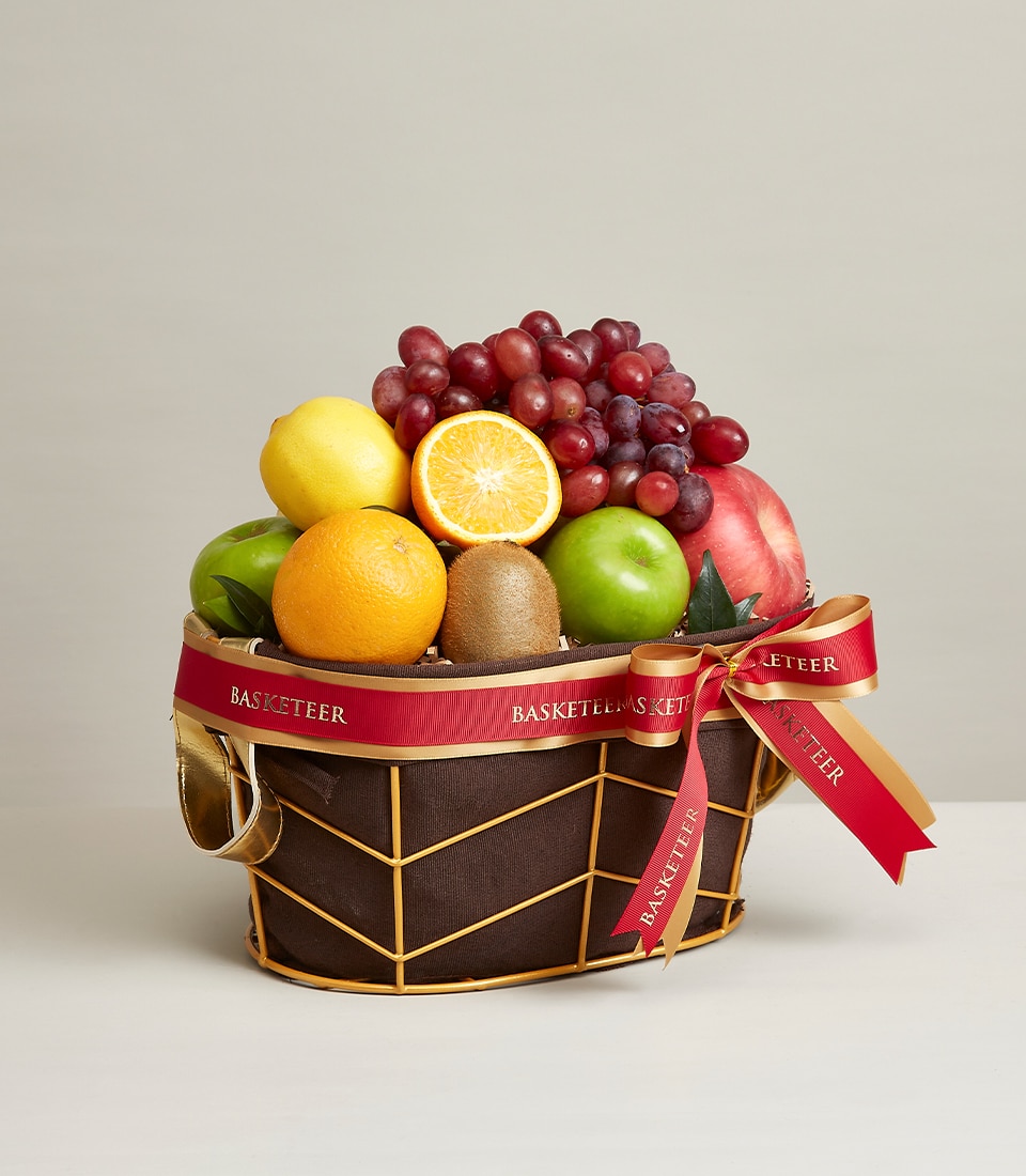 A lavishly designed decorative basket brimming with the freshest fruits: plump red grapes, a tantalizingly sliced orange, crisp apples, an exotic kiwi, a vibrant lemon, and a tempting pomegranate. The elegant gold frame of the mixed fruit basket is beautifully complemented by a luxurious red ribbon bearing the 