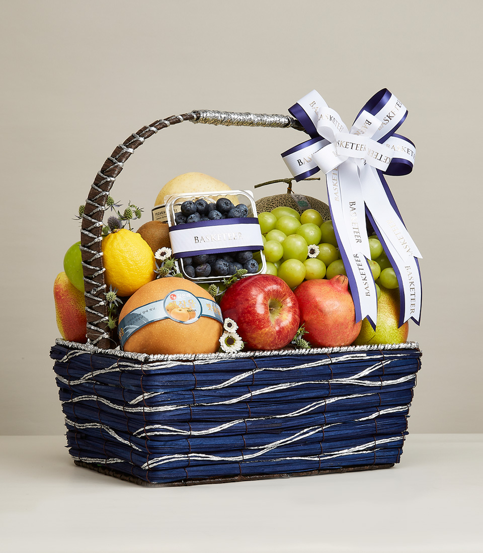 A navy blue gift basket Filled with a variety of fresh fruits such as red apples, green grapes, oranges, and many more. Beautifully decorated with bows, navy blue and white ribbons with 