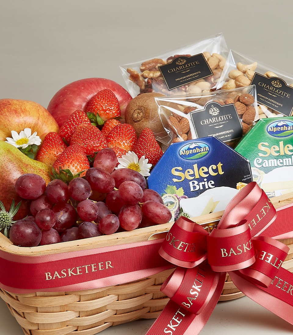 An opulent fruit, cheese, and nut gift basket exquisitely curated by Basketeer. This exquisite arrangement boasts an array of fresh, luscious fruits including crisp apples, vibrant strawberries, succulent grapes, and tangy kiwis. Accompanied by gourmet packets of mixed nuts and two decadent types of cheese: creamy Brie and indulgent Camembert. The entire presentation is elegantly adorned with a luxurious red ribbon embossed with the prestigious 