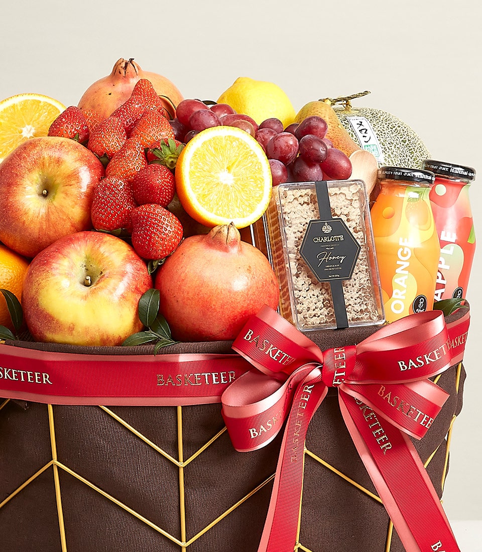 A lavish gift basket curated by Basketeer, brimming with an exquisite selection of fresh fruits and gourmet snacks. This indulgent offering features succulent apples, zesty oranges, luscious strawberries, juicy grapes, a ripe melon, and a majestic pineapple. Nestled among the fruit is a delightful package of pure honeycomb and two refreshing bottles of premium juice. The basket is elegantly adorned with Basketeer's signature red ribbon, adding a touch of sophistication to this inviting ensemble.