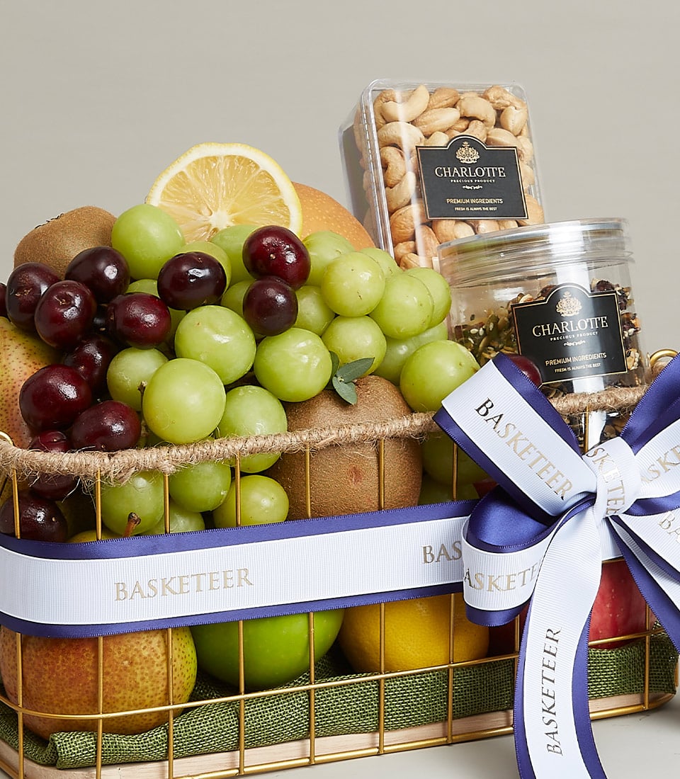 An opulent gift basket overflowing with a vibrant assortment of fresh fruits, including succulent green grapes, luscious red grapes, tangy kiwis, crisp apples, a zesty lemon, and a perfectly ripe pear. Nestled among the fruits are two elegant jars filled with gourmet nuts. The entire arrangement is exquisitely adorned with a luxurious blue and white ribbon proudly emblazoned with the 
