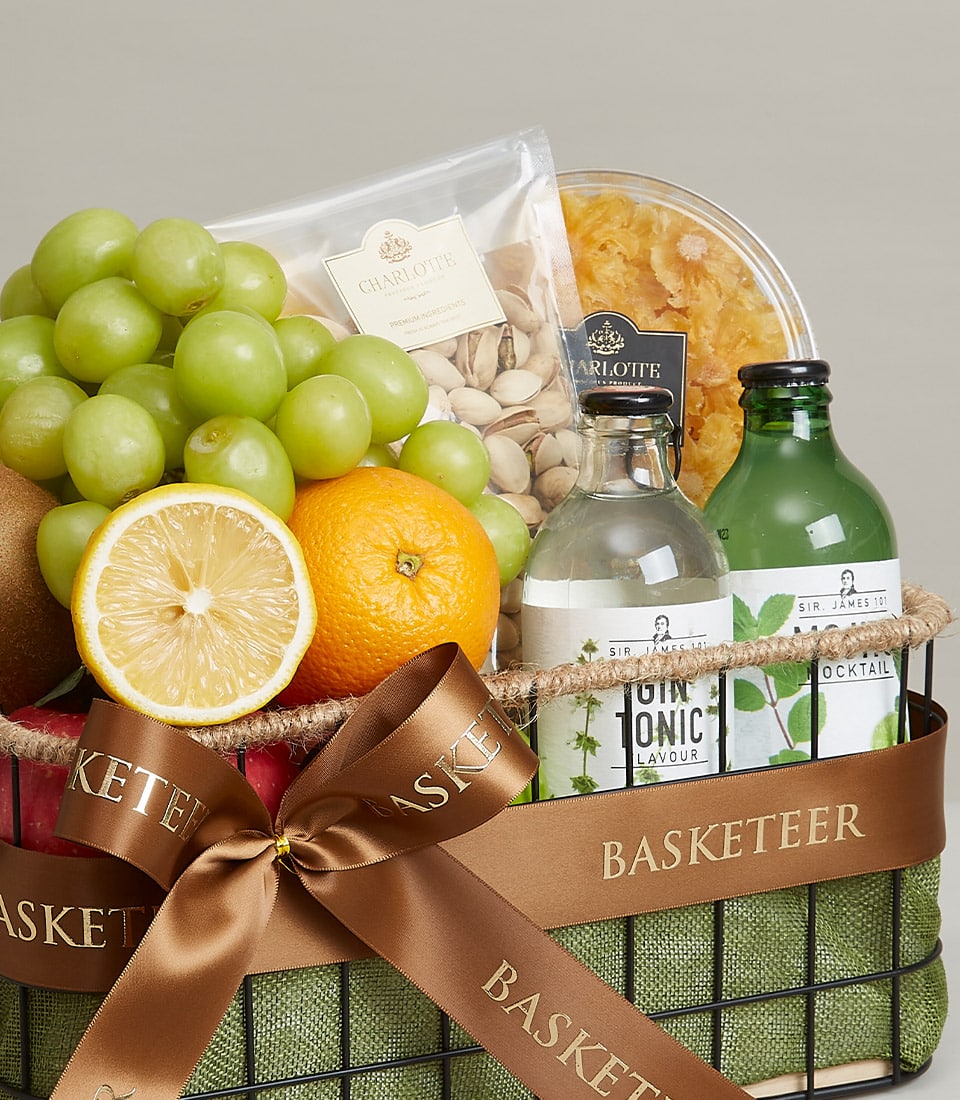 A luxurious gift basket brimming with an array of exquisite delights promises a feast for the senses. Nestled within a lush green cloth lining, discover plump, juicy green grapes, a vibrantly fresh halved lemon, and a sun-kissed orange. A luscious kiwi complements the vibrant assortment. Savory gourmet pistachios and sweet dried pineapple add indulgence to this delectable collection. Complete with a refined bottle of tonic water and an enticing green beverage bottle, this curated selection exudes sophistication. Adorned with a rich brown ribbon proudly displaying 