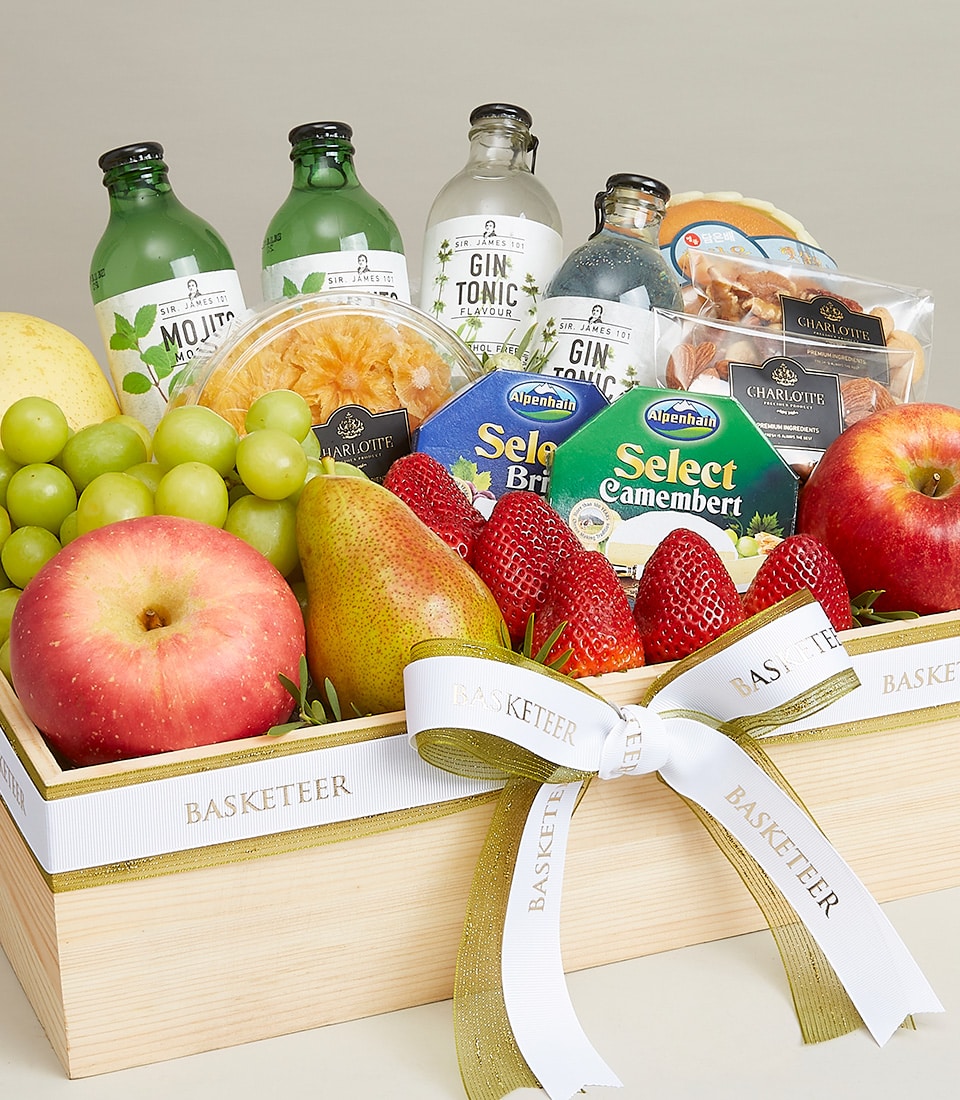 An opulent wooden gift basket showcasing a sumptuous array of fresh, vibrant fruits including apples, strawberries, grapes, and a perfectly ripened pear. Nestled among the fruits are gourmet cheeses, sparkling beverages, and an assortment of elegantly packaged snacks. The entire ensemble is beautifully adorned with a pristine white ribbon exquisitely labeled 