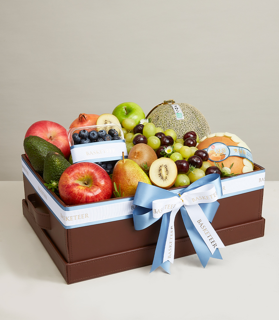 A brown gift box Filled with various types of premium grade fresh fruits such as green grapes, red cherries, green kiwis and more, decorated with light blue and white ribbon bows with 