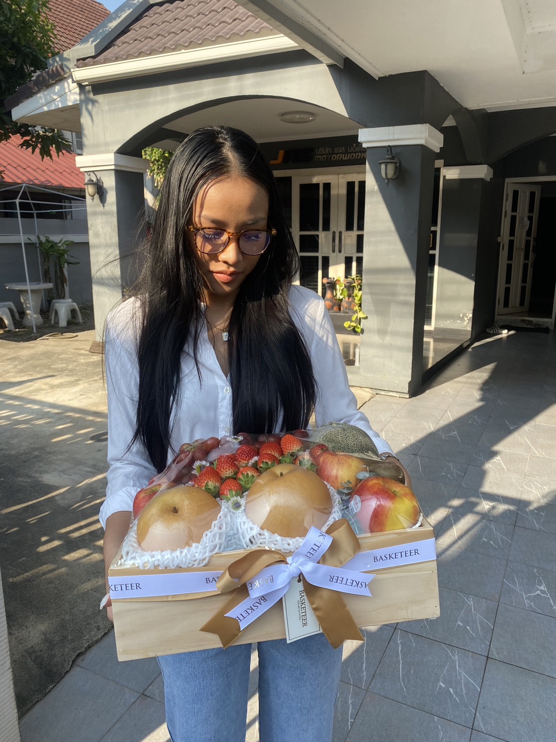 Wooden gift box with fresh Korean pears, strawberries, apples, grapes, and melons, held by a customer by Basketeer.