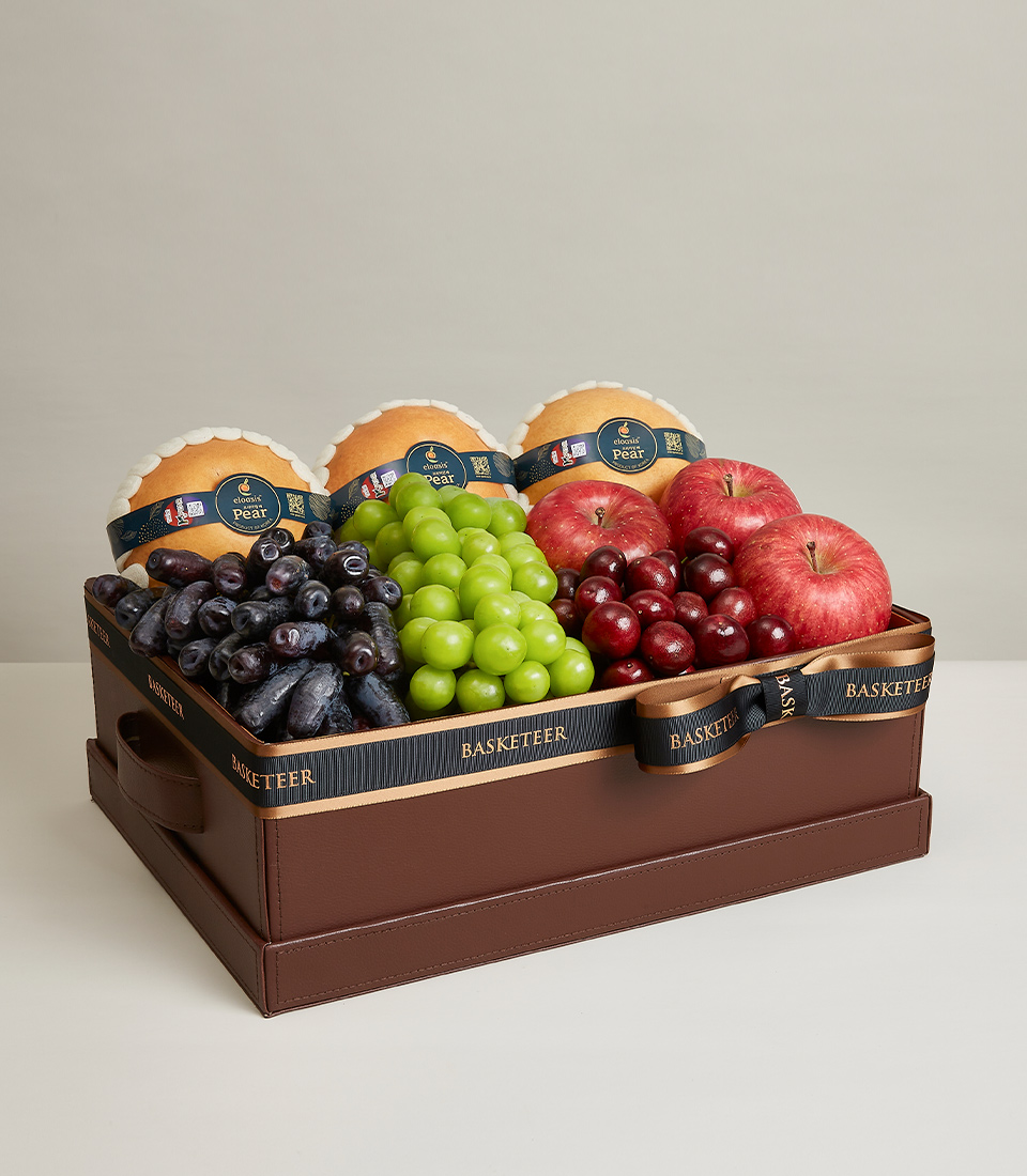 A brown big gift box Filled with various kinds of fresh fruits such as red apples, green grapes, red cherries, etc., it is decorated with gold and black ribbon bows with 