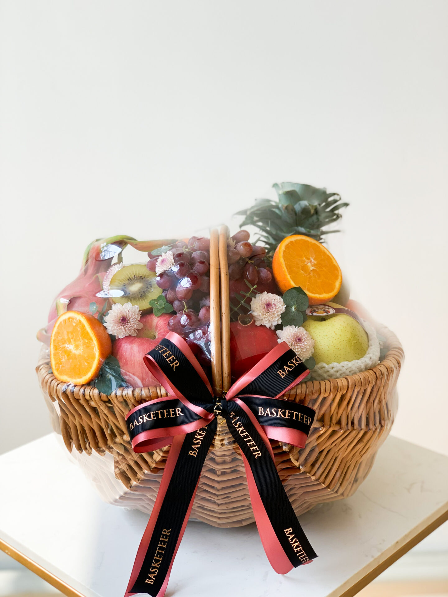 An Orchard Fresh Fruits Hamper, this wicker basket adorned with a black and red 