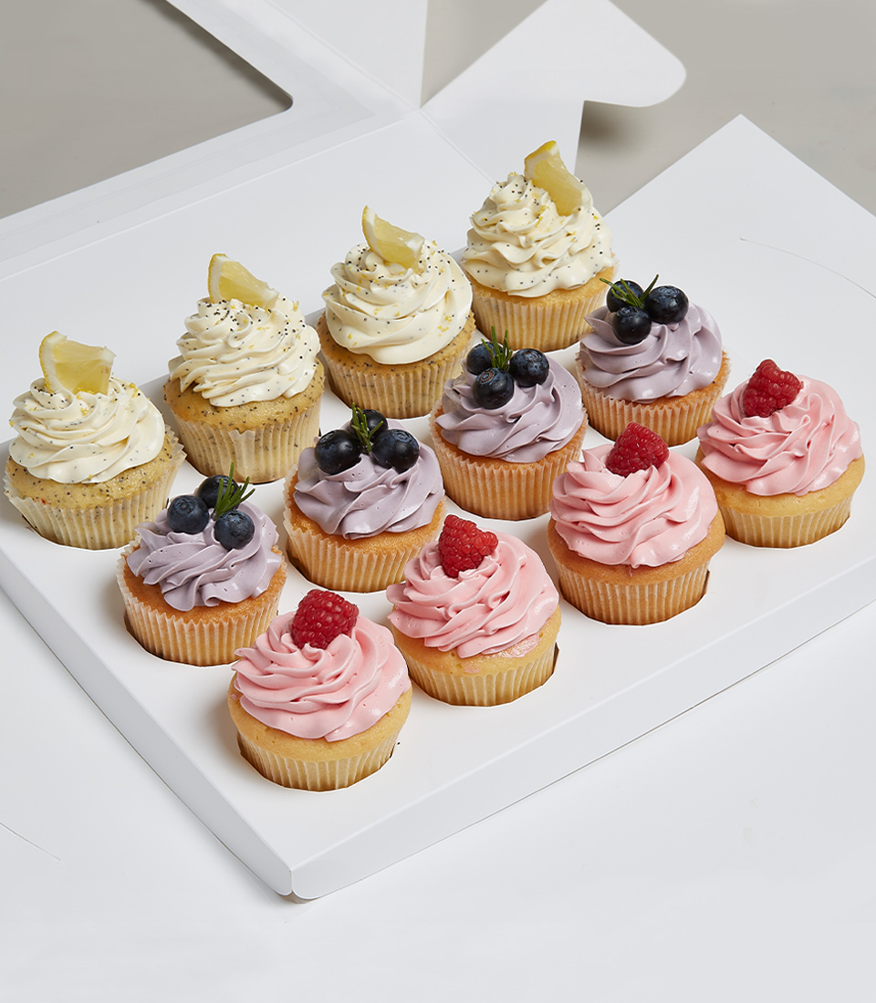 Mix And Match Berry Selection Cupcakes, Perfect Poppyseed And Lemon Curd Cupcakes, Rather Raspberry Jam Centred Cupcakes, Blueberry Belly Cupcakes in the white box tied with a white ribbon screenprinted with the Charlotte brand. Delivered express within 2 hours in Bangkok