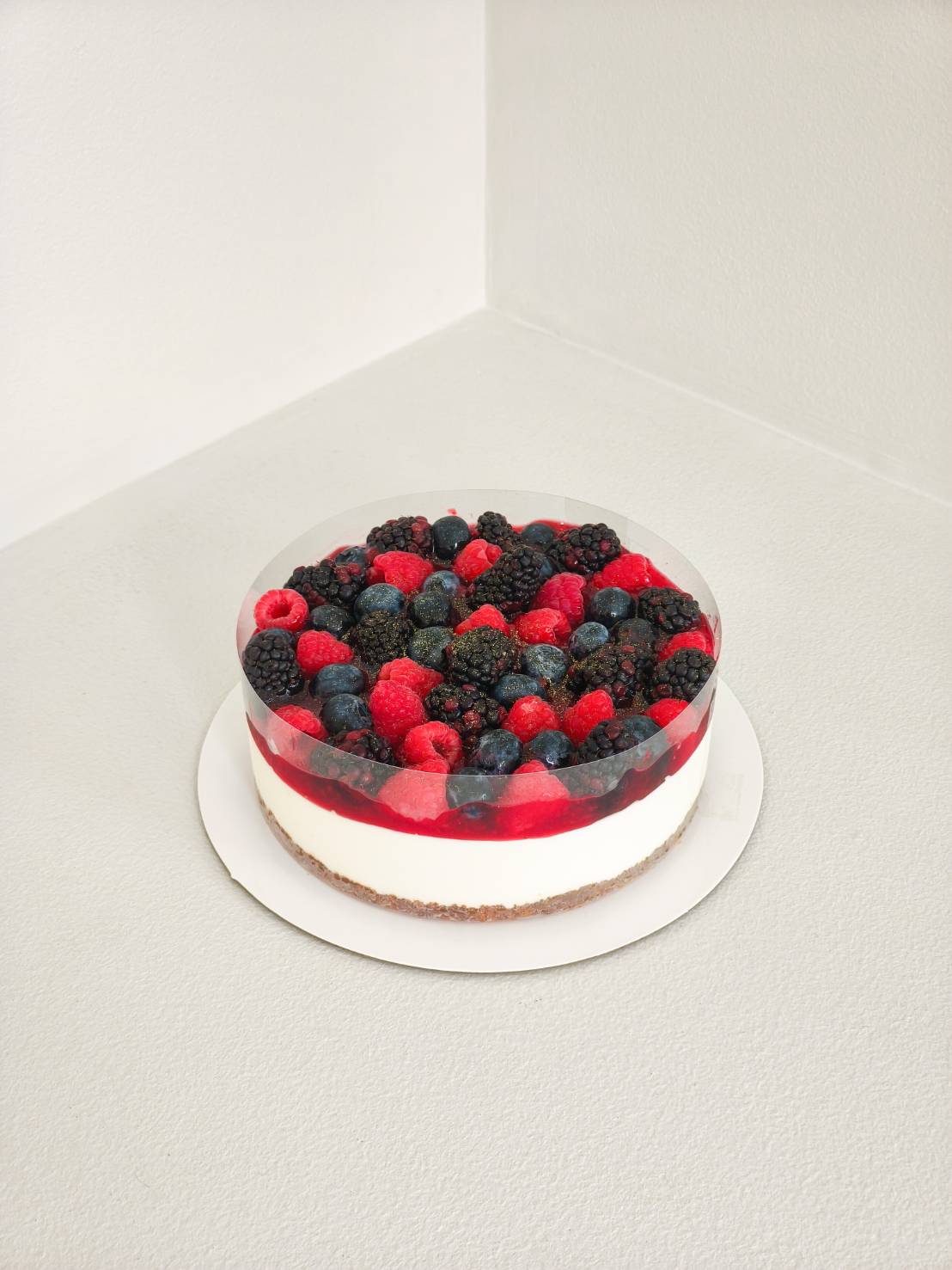 Mixed berry cheesecake with raspberries, blueberries, and blackberries on a biscuit base and creamy cheese filling.