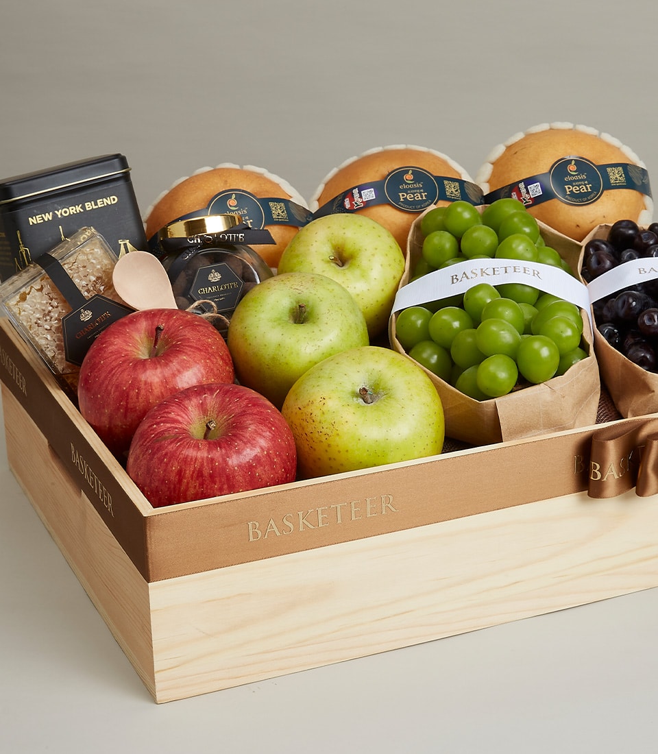 A beautifully crafted wooden crate, meticulously filled with a delectable assortment of fresh, crisp green and red apples, succulent green and dark grapes. Alongside the fruits, discover an exquisite package of premium tea blend, perfect for indulgent moments. The crate is elegantly adorned with a luxurious brown ribbon and proudly displays the distinguished 