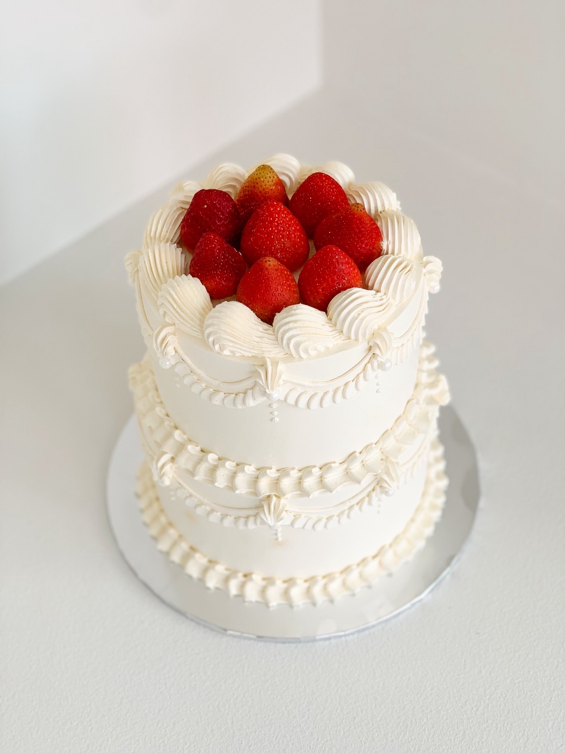 Classic two-tier vintage cake with piped cream and fresh strawberries on top