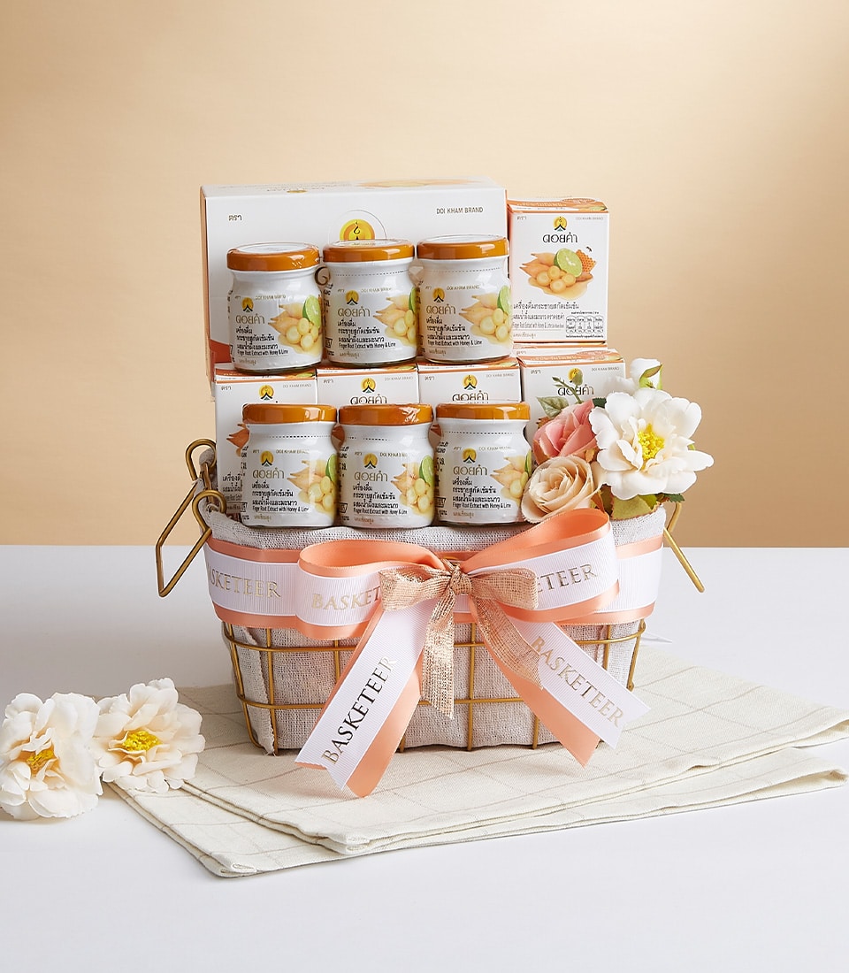 A luxurious gift basket elegantly showcases jars of Bird's Nest beverage by Brand's. The sophisticated arrangement is accentuated with peach-colored ribbons and pristine white flowers, each detail exuding elegance and refinement. Delicate gift tags add a personal touch, while the ribbon proudly displays the Basketeer logo, signifying the thoughtful curation synonymous with this distinguished brand. The entire setup radiates opulence as it rests upon a crisp white cloth against a softly lit backdrop.