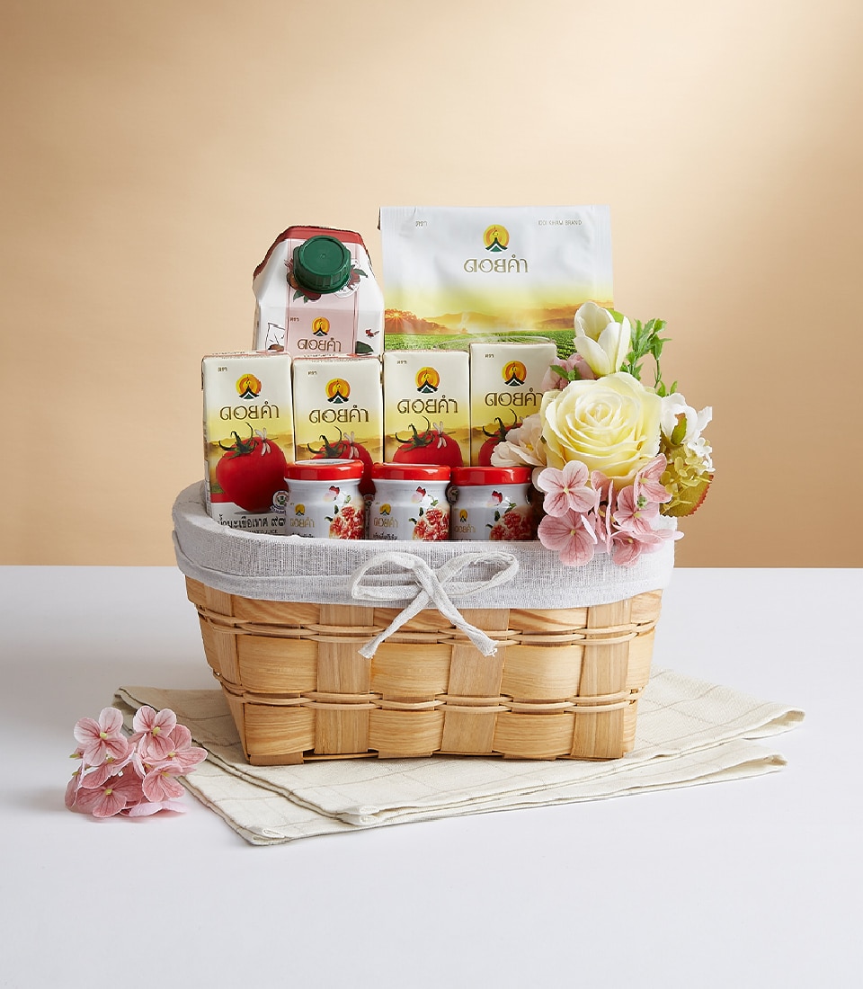 A beautifully crafted wicker basket overflowing with an exquisite selection of apple-themed delicacies. Nestled within, you'll find cartons of premium apple juice, luscious apple-flavored snacks, and charming small jars adorned with vibrant red lids. The basket is elegantly decorated with delicate artificial flowers and wrapped in a pristine white cloth. Showcased against a sophisticated, light beige background, this luxurious arrangement proudly features ribbons and packaging embellished with the prestigious Basketeer logo, inviting you to indulge in unparalleled elegance and taste.