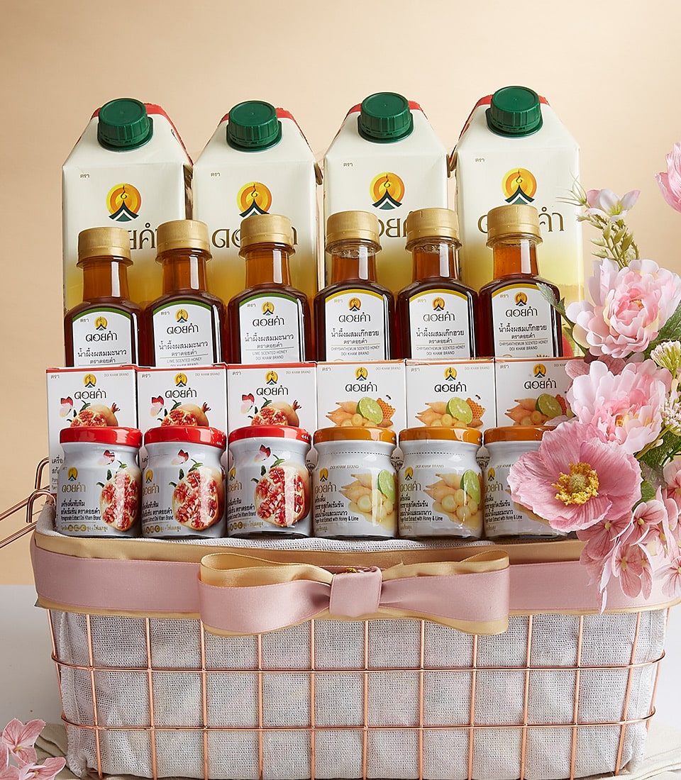 A luxurious gift basket from Basketeer, artfully arranged with an exquisite assortment of premium beverages. At the back, six large cartons of gourmet juices stand tall, while an array of elegantly bottled drinks graces the middle. The front showcases a delightful selection of artisanal jelly jars. The entire ensemble is adorned with delicate pink flowers, beautifully complementing the sophisticated presentation. A refined ribbon featuring the Basketeer logo adds a touch of elegance to this inviting scene.