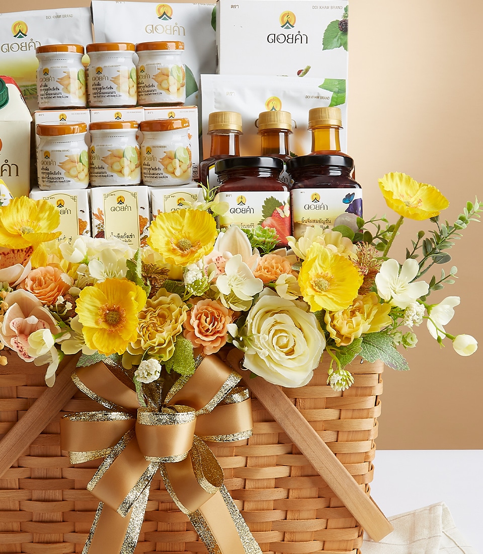 A lavishly appointed gift basket, wrapped in a luxurious gold and white ribbon featuring the Basketeer logo, brimming with an exquisite selection of jars, bottles, and packages all elegantly labeled with 
