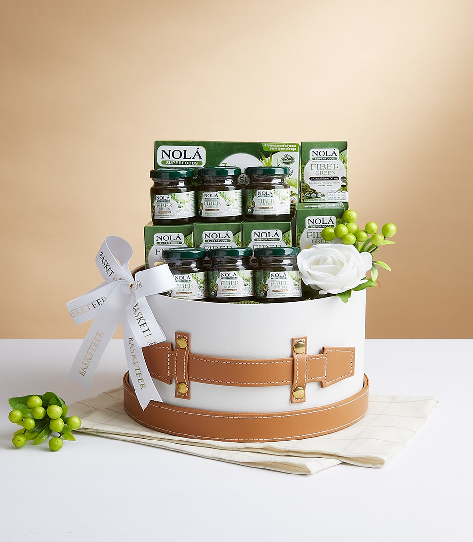 A luxurious gift basket featuring an elegant white and brown hatbox design, beautifully adorned with a pristine white ribbon bearing the Basketeer logo. The centerpiece includes an assortment of premium 